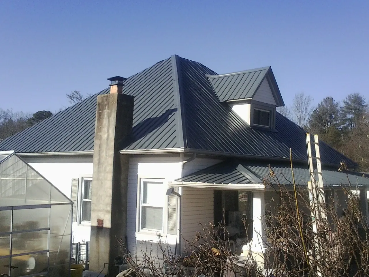Dark blue standing seam metal roof on a white farmhouse with dormer — Slate & Tile Roof Repair by Roofing Brothers in Kanarraville
