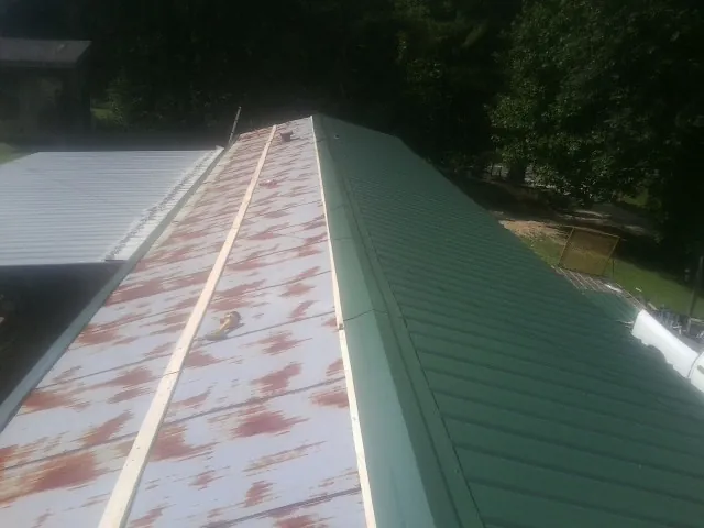 Old rusted panels beside newly installed green metal roofing — Wind Damage Roof Repair by Roofing Brothers in Kanarraville
