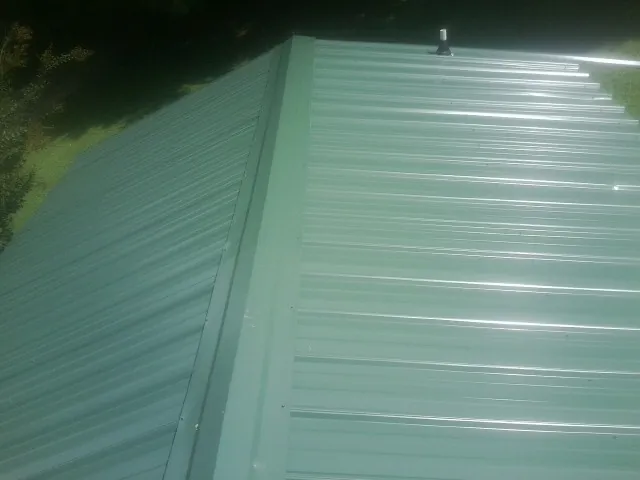 New green metal panels meeting at the ridge of a roof — Flat Roof Repair work by our crew in Kanarraville