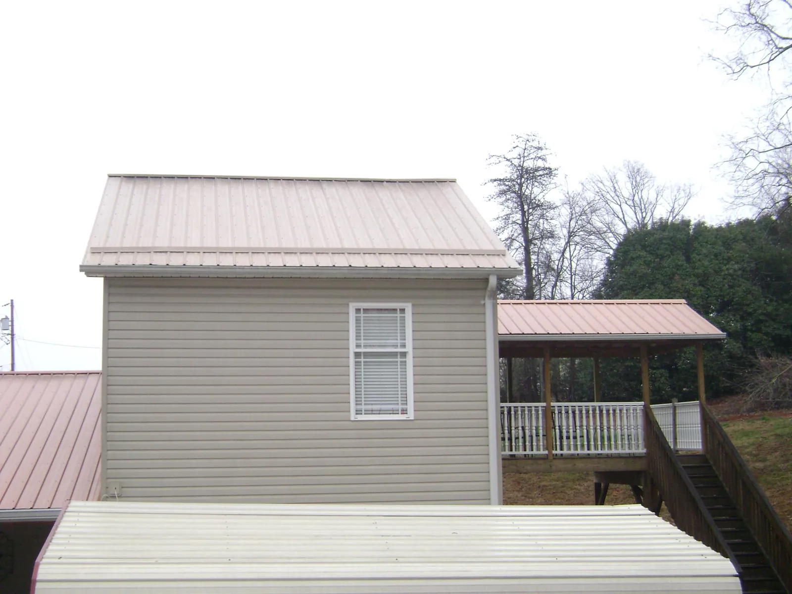 Tan metal roofs on a two story addition and attached porch, from a Roof Replacement job in Kanarraville